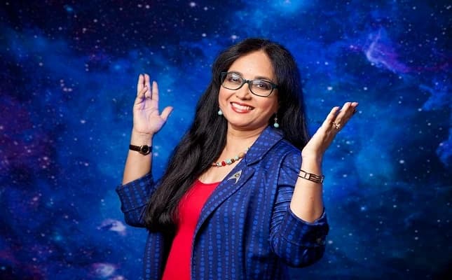 Professor Shirin Haque, WISH founder and astronomer, standing before a painted galaxy